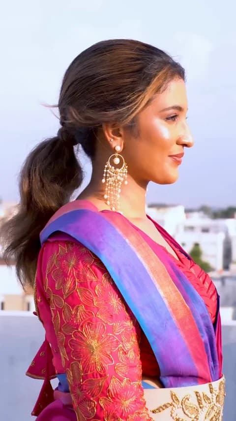 Pearl drop earrings shown from the front and side with a pink and blue outfit.